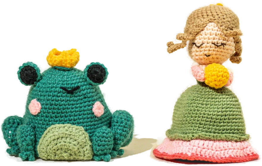 Two handmade crochet figures — a green frog prince and a doll in a green dress